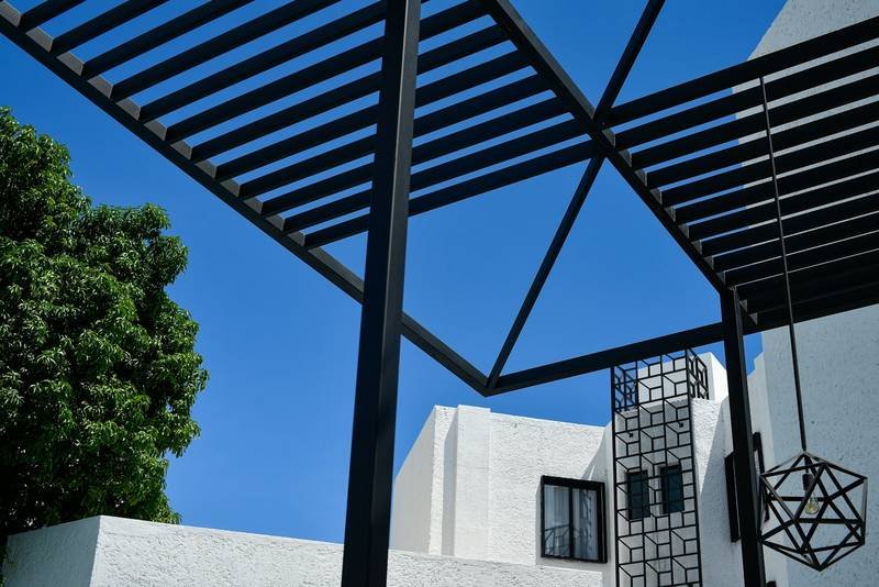 Pergola métallique noire devant une façade blanche